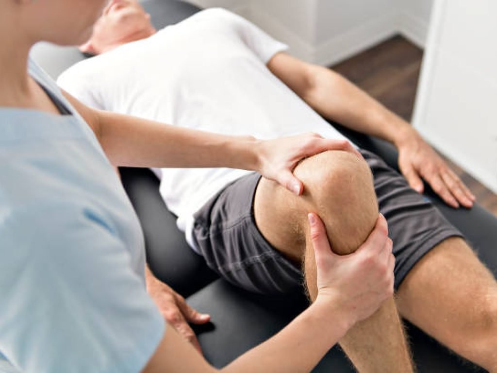 A Patient at the physiotherapy doing physical exercises with his therapist